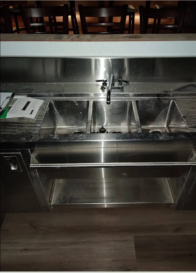 Commercial three-compartment sink and service-area equipment at Beach Pit BBQ